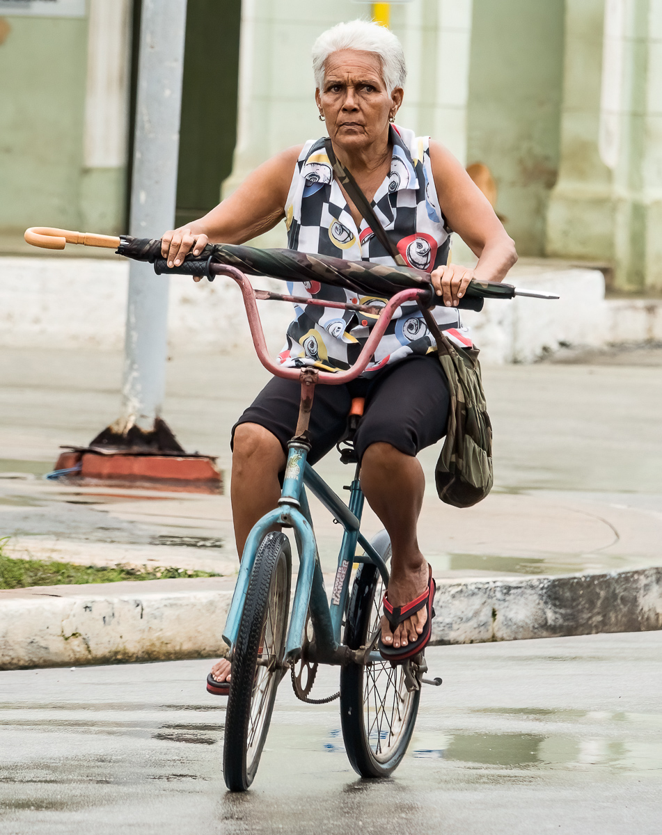 Woman riding a bicycle with umbrella, Remedios