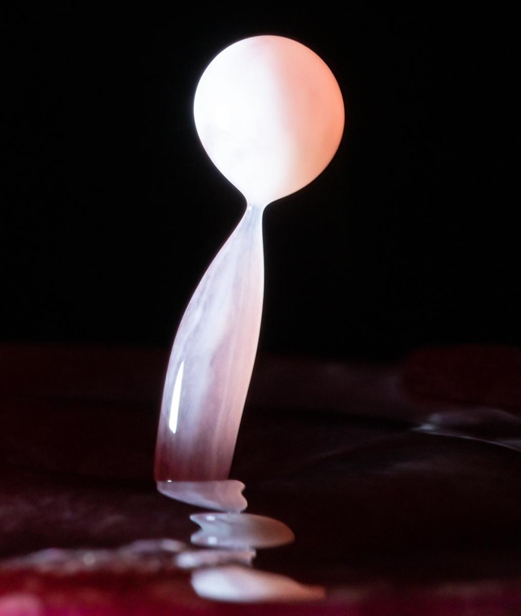 Milk droplet landing in red-dyed water